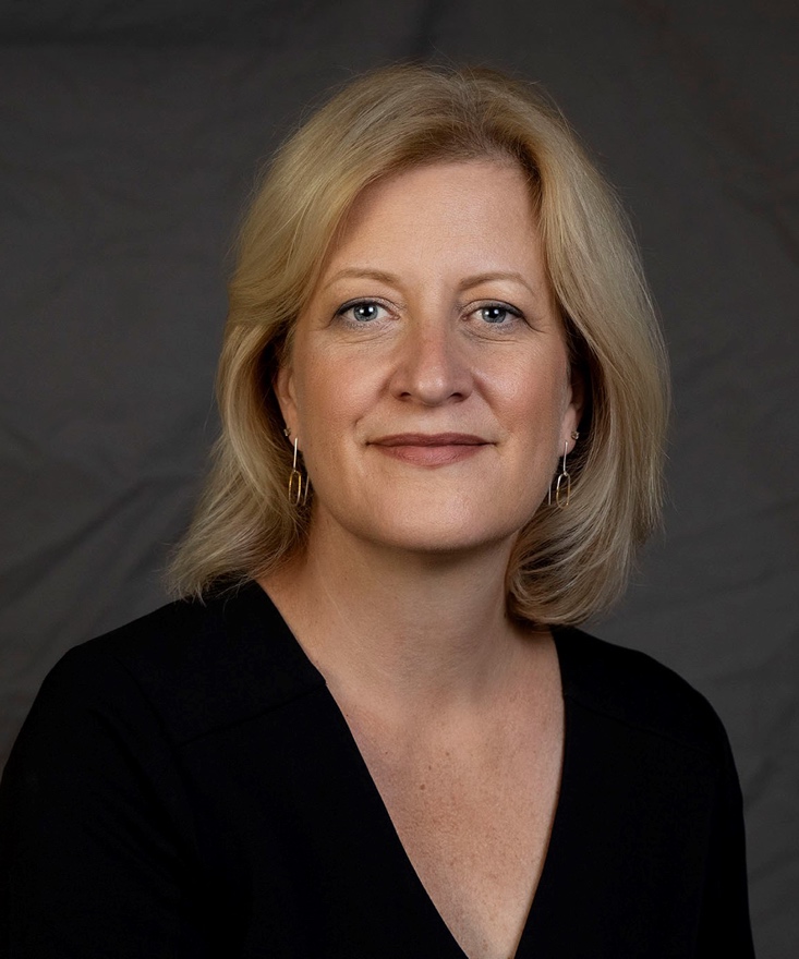 A white woman with blonde hair is smiling at the camera